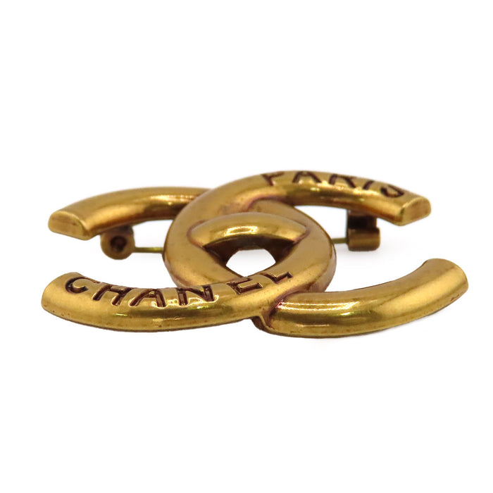 CHANEL  
COCO CC B21K métal couleur or  
Broche logo tourniquet Coco Mark