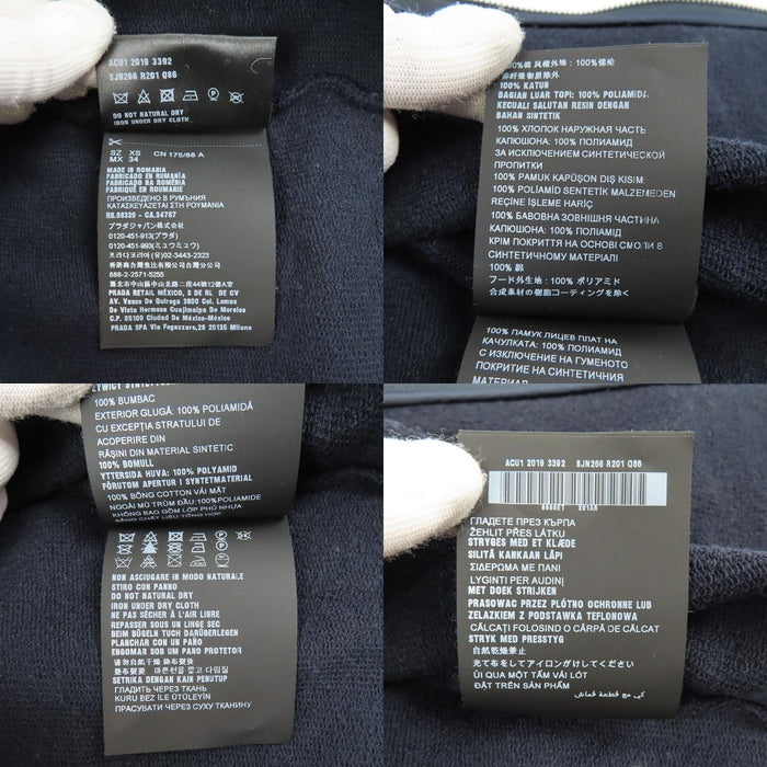 PRADA  
Sweat à capuche en coton avec logo en caoutchouc et empiècements en nylon  
Veste zippée avec logo latéral